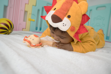 Cute asian baby lying and play lion teddyの写真素材