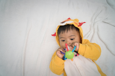 Cute asian baby lying on bed and play toysの写真素材