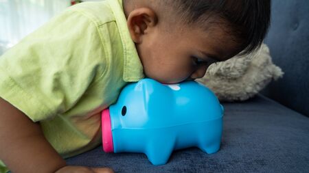 Cute little asian boy with piggy bankの写真素材