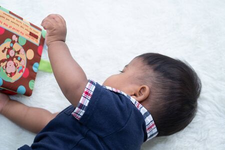 Cute little baby boy reading the book