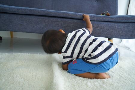 Cute little baby  looking under the sofa