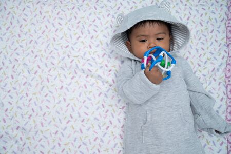 cute little asian baby boy lying on soft blanket and play toy