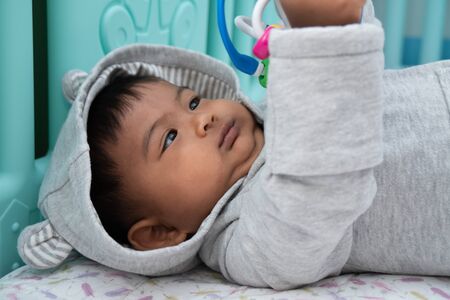 cute little asian baby boy lying on soft blanket and play toyの写真素材