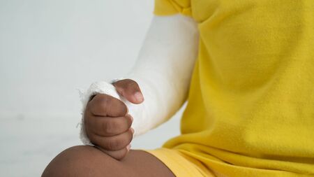 Cute boy hand bone broken from accident with arm splintの写真素材