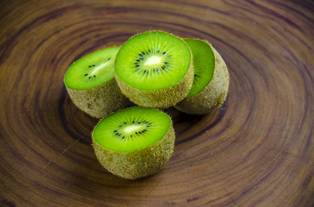 Sliced fresh and juicy kiwi fruit halves on a wooden background.の写真素材