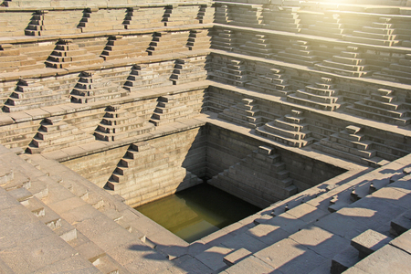 Stepped tank with green water in Pushkarani, Hampi, Karnataka, India. Queens bath. Background geometry. Sacred geometry. Royal enclosure.の写真素材