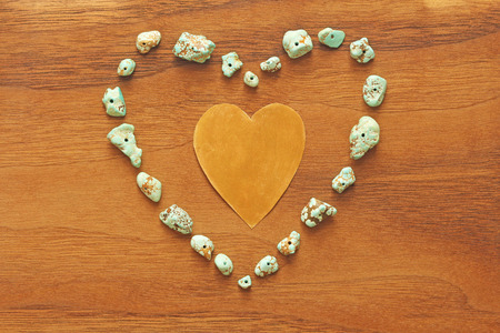 Turquoise stones on a background of natural wood black walnut. Blue color stone. Collection of minerals and natural stones. Heart made of natural stones. A beautiful heart.の写真素材