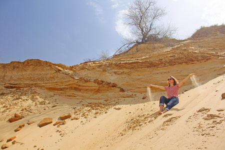 A girl in the desert lets the sand through her fingersの写真素材