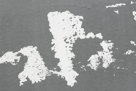 Old flaky paint peeling off a grungy cracked wall. Cracks, scrapes, peeling old paint and plaster on background of old cement wall. An old cement stone wall as vintage cracked. Gray, white background.の写真素材