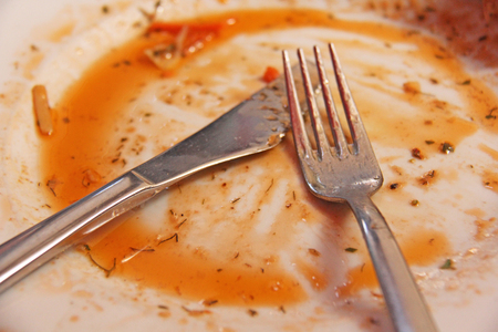 Dirty Plate After Eating. Dirty Fork and Dirty Knife Lie on the Dirty White Plate. Dirty Instruments For Food.の写真素材