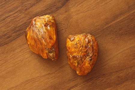 Amber raw unprocessed natural mineral stone amber, a collection of natural stones on a background of natural wood black walnut. A beautiful untreated stone. Flat lay.の写真素材