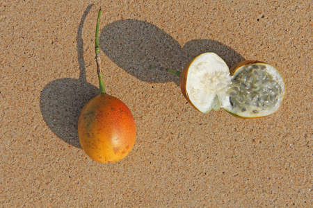 Two orange open passion fruit with seeds. Passion fruit closeup on the beach, on the sand and on the...