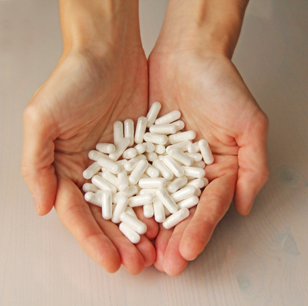 White Capsules or Tablets in Female Hands. Many Tablets Lie in Hands. Healthy lifestyle.の写真素材