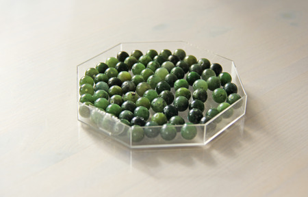 Natural green jade nephrite mineral stones beads. Green and grassy natural background made of round...