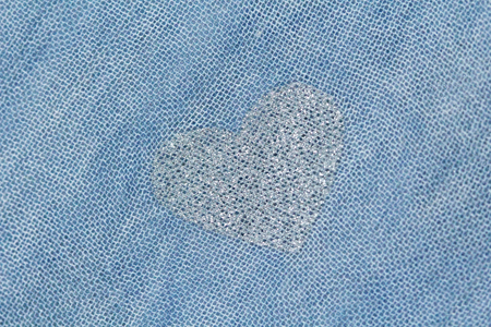 Silver heart on a blue background of cotton fabric. Romantic pastel background. Design with copy...
