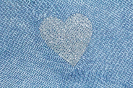 Silver heart on a blue background of cotton fabric. Romantic pastel background. Design with copy...