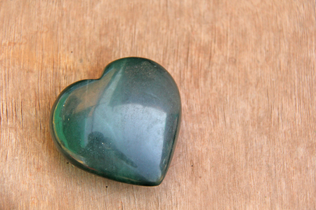 Green heart made of natural stone jade. A heart shaped stone lies on a brown or beige background. Love talisman, zen, spa.の写真素材