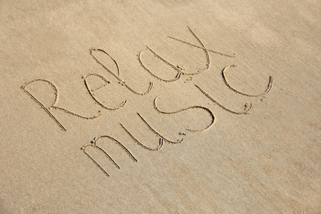 The inscription of relax music is painted on the sand.の写真素材
