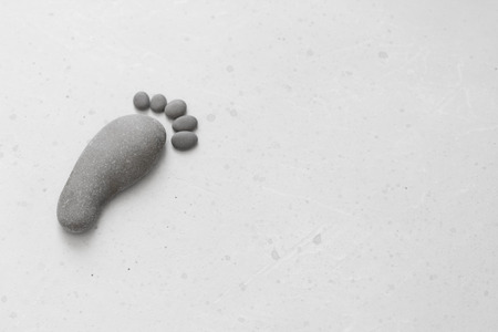 Footprints made of stones. Happy feet. Stone arranged like footprints on the beach. Spa background with grey stones. Copy space for your text. Aromatherapy for beauty, relaxation, nature massage.の写真素材