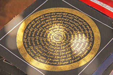 The golden mantra in the circle is painted on black paper and is sold on the market in India. Gift souvenir India Tibet Bazaar.の写真素材