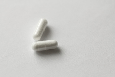 White Transparent Capsules or Tablets on the White Background. Medications and Pills. Health, Treatment and Longevity.の写真素材
