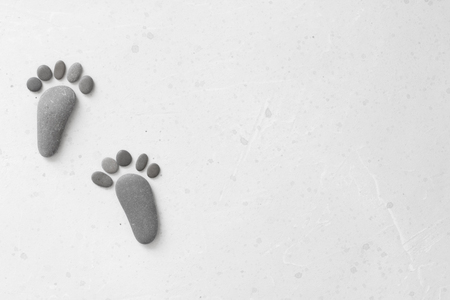 Footprints made of stones. Happy feet. Stone arranged like footprints on the beach. Spa background with grey stones. Copy space for your text. Aromatherapy for beauty, relaxation, nature massage.の写真素材