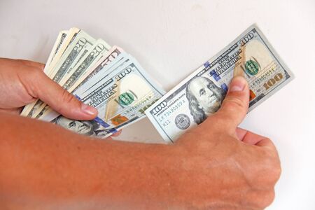 The man's hand holds US dollars, counts them and pays. Paper money dollars in hand.