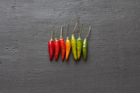 Red Hot Chili Peppers On Background or Black Table. A Lot of Red Chilli Peppers. Green, Yellow Hot...