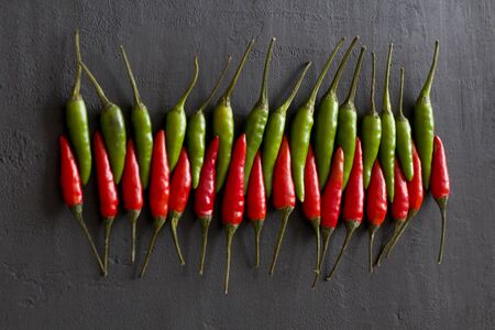 Red Hot Chili Peppers On Black Dark Background on Black Table. A Lot of Red Chilli Peppers. Copy space for your text. Flat lay, top view. Red and Green Chili Peppers. Penetration, erotica.の写真素材