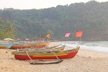 Bright colorful boats with flags for catching fish stood on the shore of the Indian Ocean. India, Goa.の写真素材