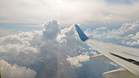 Airplane wing view out of the window on the cloudy sky background. Holiday vacation background. Wing...