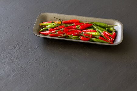 Red Hot Chili Peppers On Black and Dark Modern Background or Black Table. A Lot of Red Chilli Peppers. Green Hot Chili Peppers. Copy space for your text. Flat lay, top view.の写真素材