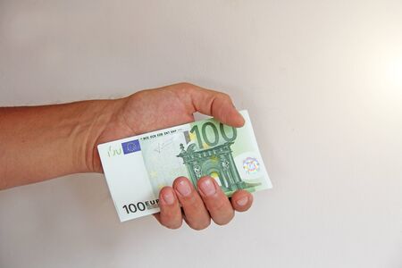 The man's hand holds the 100 euro, considers them and pays. Paper money euros in the hands.の写真素材