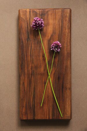 Wild onion violet on a wooden background of black walnut. Beautiful summer wildflowers. vertical, vertical design.の写真素材