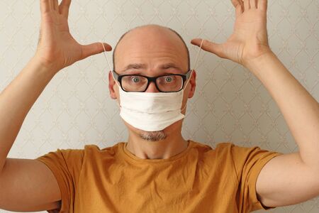 Man puts on disposable protective white medical hygiene mask to protect himself from respiratory, infectious viral diseases, from coronavirus. Protection against coronavirus, contagious disease.の写真素材
