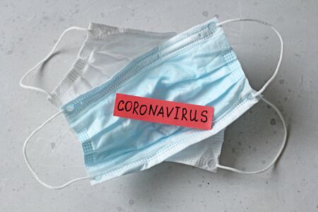 Two Medical mask which word Coronavirus is written. Surgical used mask with rubber ear straps. Typical 3-ply surgical mask cover mouth, nose. Procedure mask bacteria. Protection against coronavirus.の写真素材