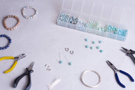 Making of handmade jewellery. Top view. Beads, tools for creating jewelry. Preparation for handmade. Create jewelry, bracelets from natural stones with your own hands. Flat lay. On white background.の写真素材