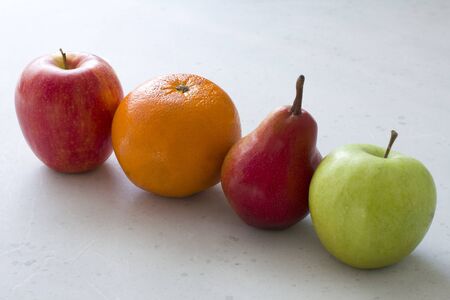 Bright and juicy fruits red apple, red pear, green apple and orange close-up lie diagonally on a...