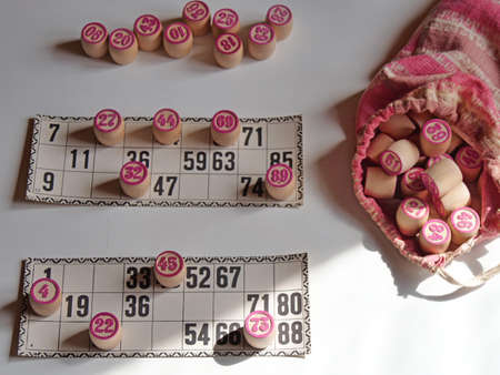 Russian lotto, bingo board game, barrels and cards on a white background. Quarantine Games Concept. Board game lotto with wooden barrels. Money game, luck, luck, excitement, board games, stay home.の写真素材