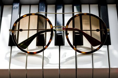 Moscow, Russia, May 20, 2020. Gucci sunglasses are popular high-end brand, created for men, women, with round dark lenses lie on black and white piano keys. Image shows Gucci logo.の写真素材