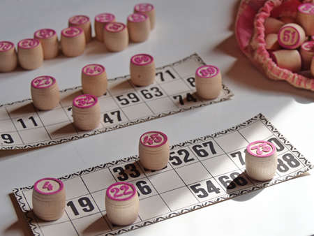 Russian lotto, bingo board game, barrels and cards on a white background. Quarantine Games Concept. Board game lotto with wooden barrels. Money game, luck, luck, excitement, board games, stay home.の写真素材