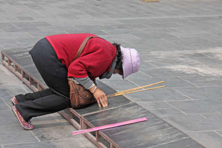 China, Shanghai - April 10, 2012. A Chinese woman prays in a Buddhist temple.のeditorial素材