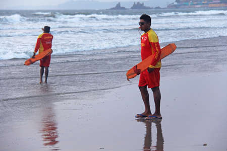 India, GOA, January 28, 2018. Men rescuers walk along the shore in red clothes, whistle in the whistle, warn of danger in the sea and expel people from the sea.のeditorial素材