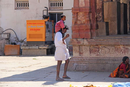 India, Hampi, 01 February 2018. A small Indian boy sits on the shoulders of the pope. Dad and son. Inside the Temple of Virupaksha.のeditorial素材