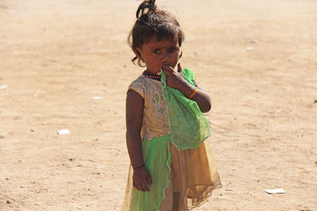 India, Hampi, 02 February 2018. A little poor girl in a dirty dress. Portrait of an indian girl. A girl from India in ornaments.のeditorial素材