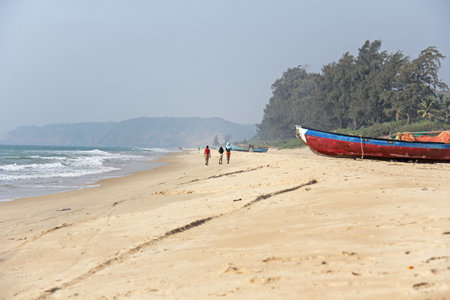 India, GOA, January 22, 2018. Indian children are walking along the seashore. Boats on the beach or on the beach.のeditorial素材