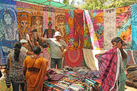 India, GOA, January 24, 2018. Indian man salesman in the Anjuna market, Goa, India. Indian markets, trade. A store of shawls and stoles.のeditorial素材