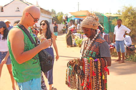 India, GOA, January 24, 2018. Street trading. Bald Tourist European buys beads or jewelry from an Indian seller. The seller on the street sells his goods. Ananda, GOA, Anjuna.のeditorial素材