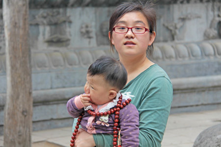 China, Shaolin - April 11, 2012. Chinese young mother girl with a child in her arms at the Shaolin Monastery, China.のeditorial素材
