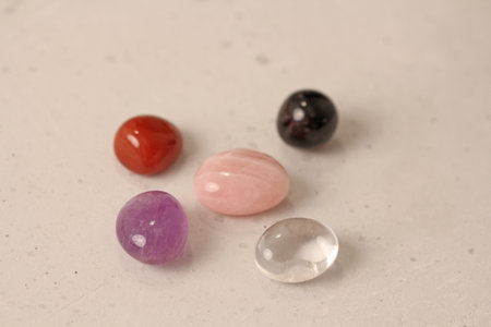A set of natural stones lies on a light white background, garnet, amethyst, carnelian, rock crystal and rose quartz. Collection of natural stones, mineral and semi-precious stones.の写真素材